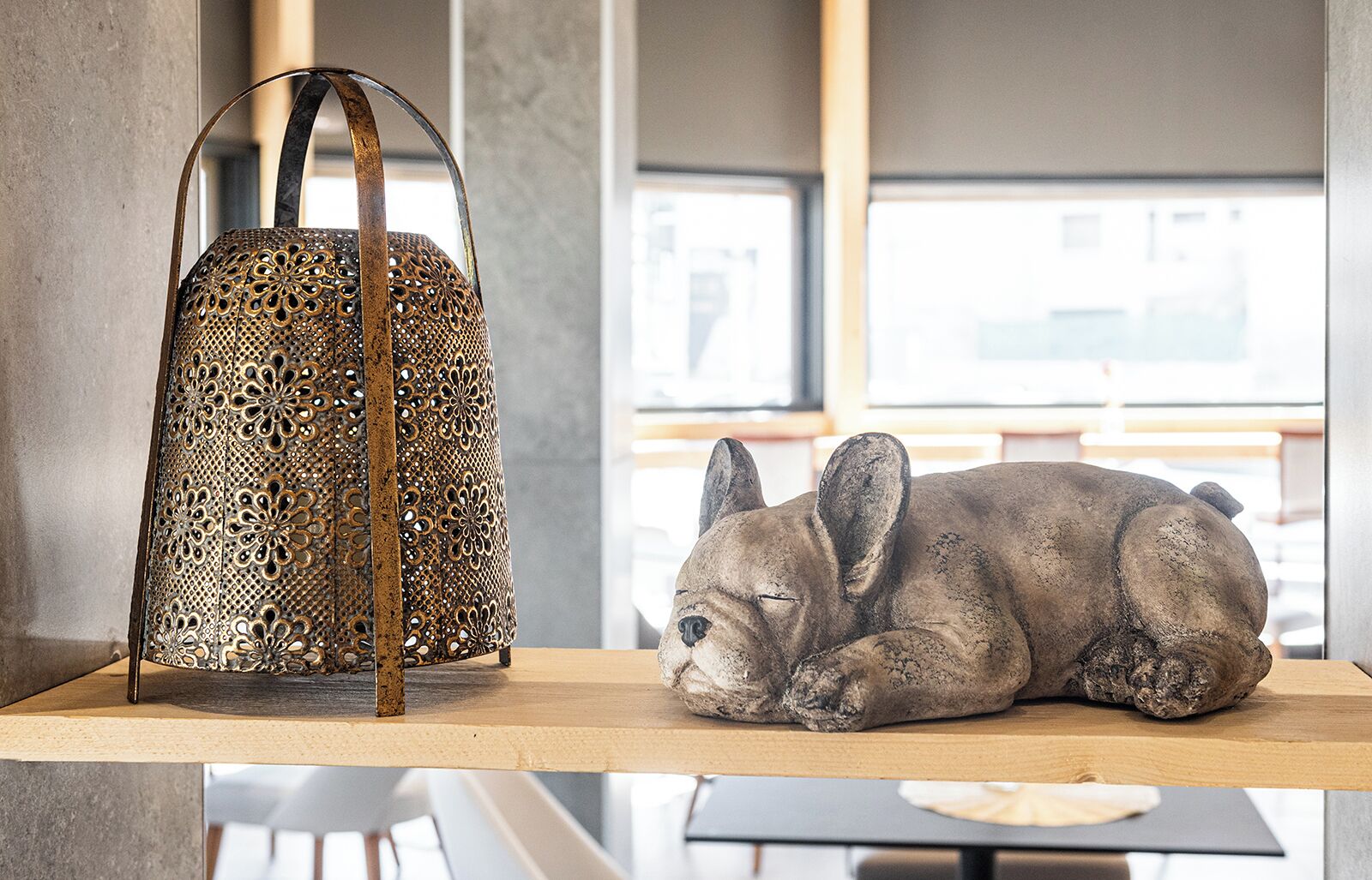 A decorative metal lantern and a sculpture of a sleeping rabbit on a wooden shelf.