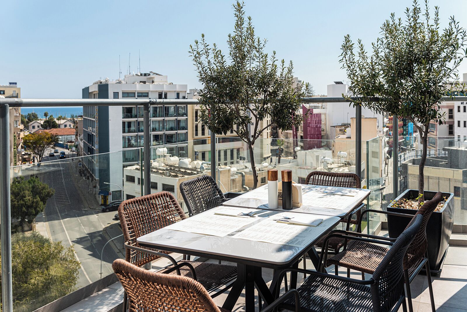 A balcony with a table and chairs, overlooking a cityscape.