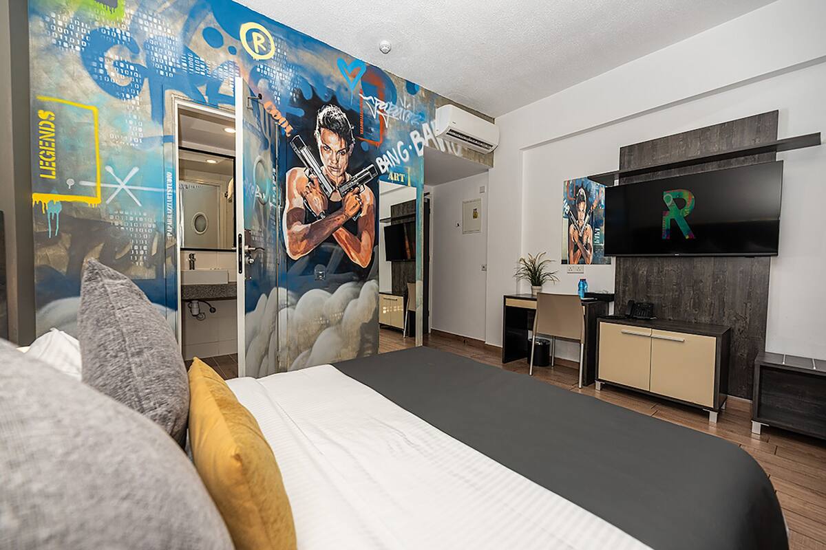 Een moderne hotelkamer met een groot bed, een bureau, een televisie en een muurschildering.