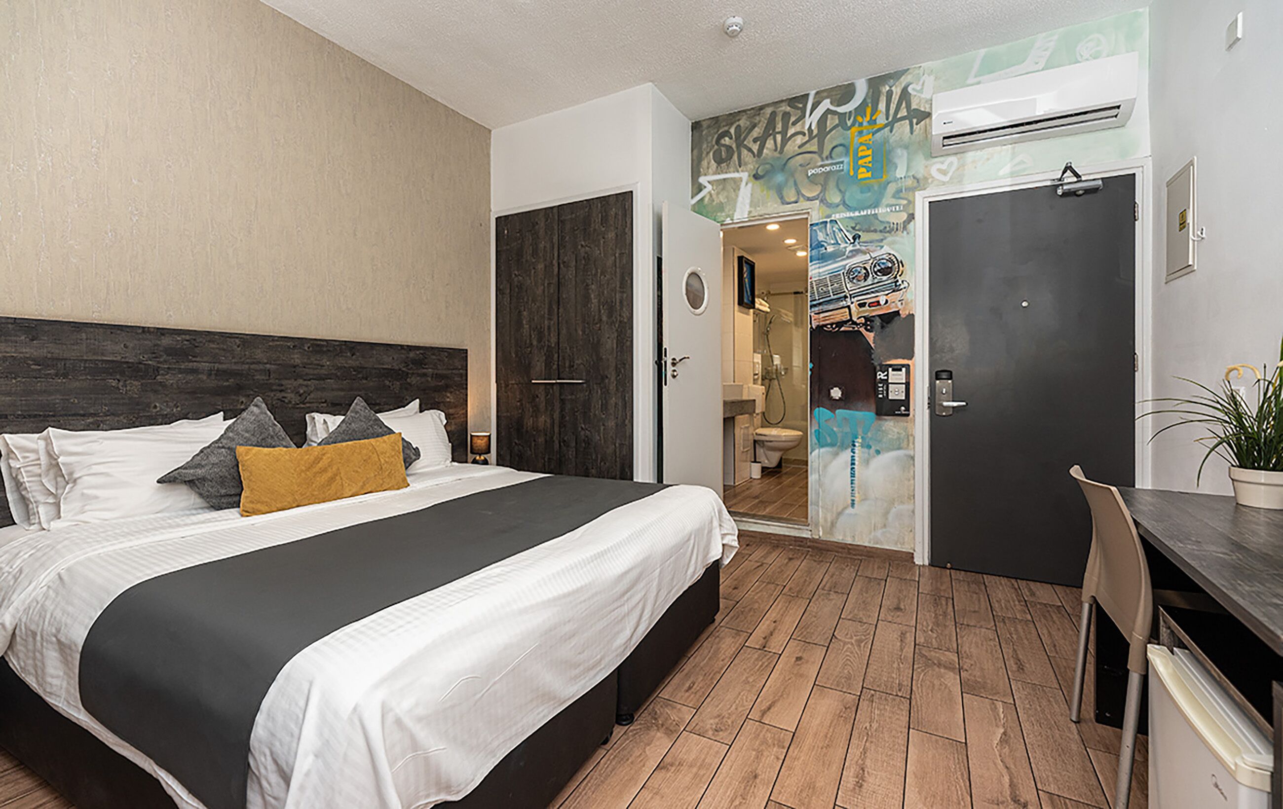 A modern hotel room with a large bed, a desk, and a shower area.