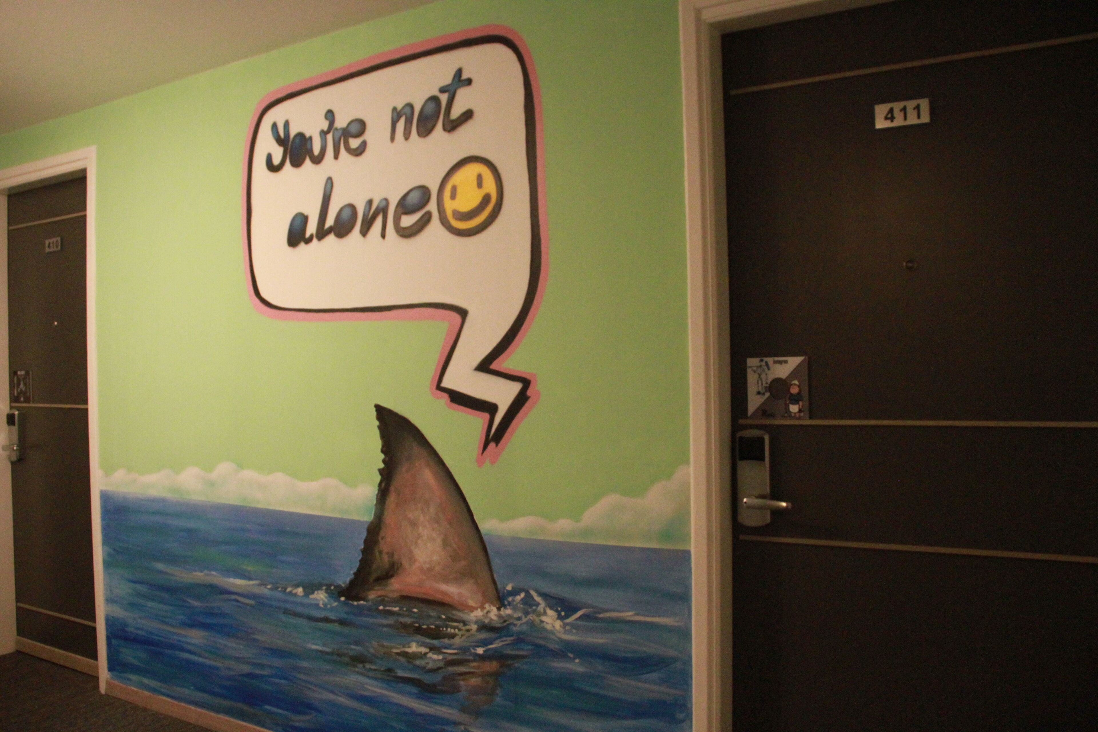 A room with a mural of a shark and a speech bubble saying "You're not alone" with a smiley face.