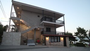 A two-story building with a stone facade, a balcony on the upper floor, and a staircase leading to the entrance. - Apollo Apartments & Studios (Kassandra)