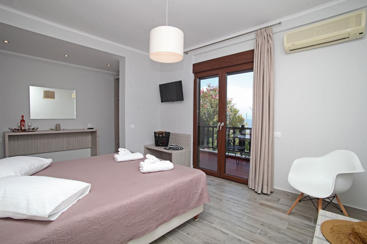 A bedroom with a bed, a chair, a TV, and a balcony.