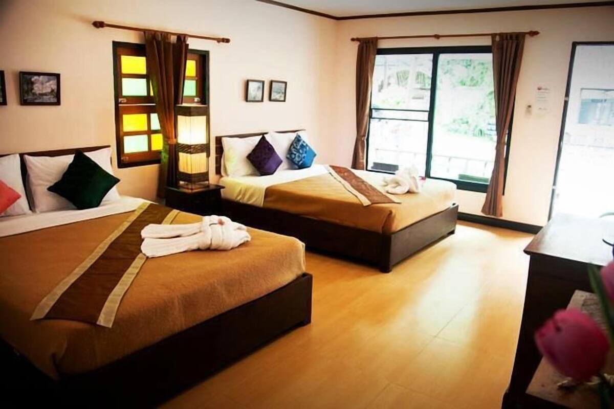 Ein Hotelzimmer mit zwei Betten, einem Schreibtisch und großen Fenstern.