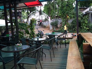 An outdoor seating area with round tables and wicker chairs, surrounded by lush greenery and a decorative archway. - The Sylvana Pai Boutique Resort (Pai)
