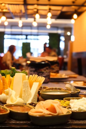 Enjoy a variety of food options at our dining table, featuring an assortment of cheeses, fruits, and condiments.