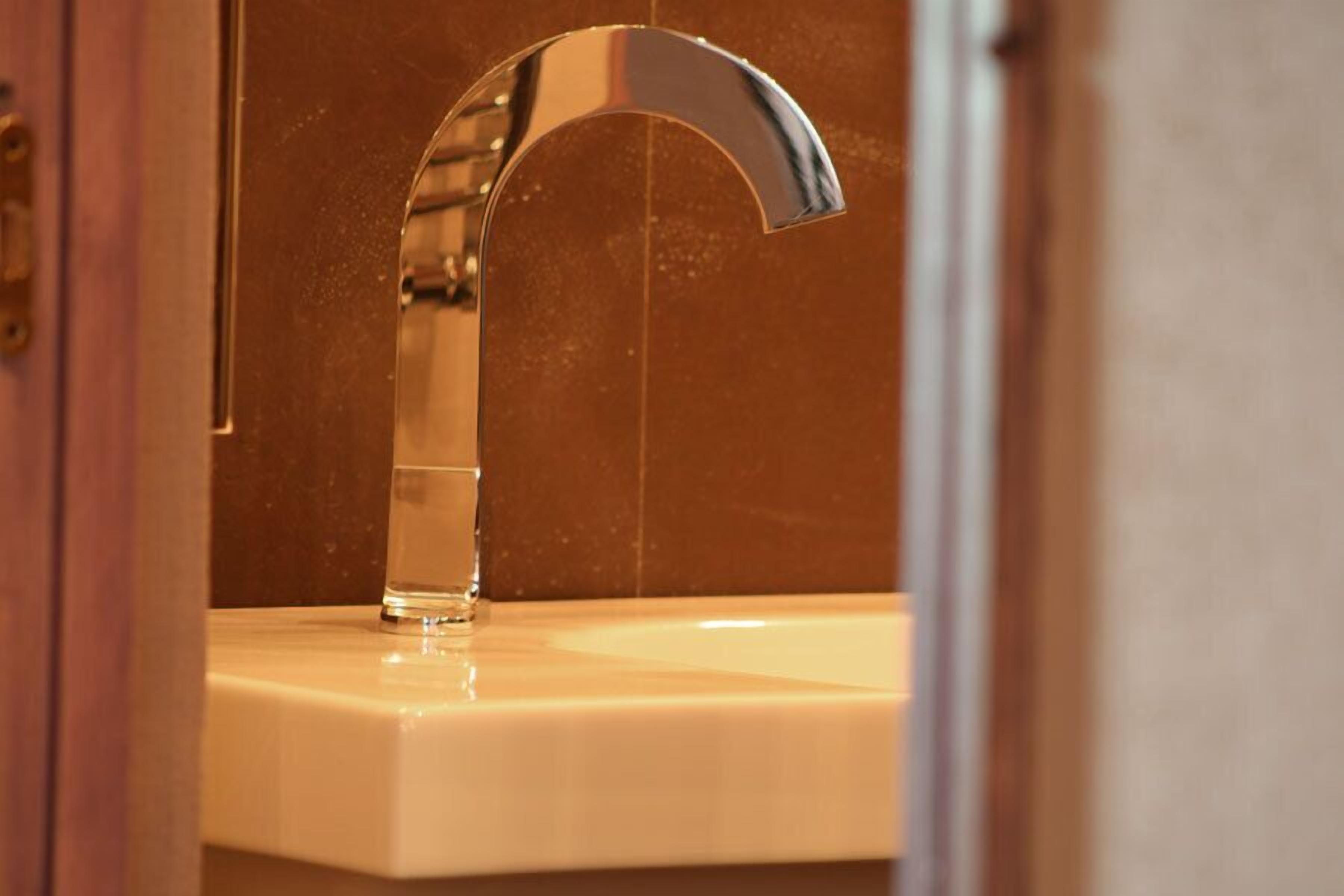 Une salle de bain dotée d’un robinet moderne en chrome et d’un lavabo beige.