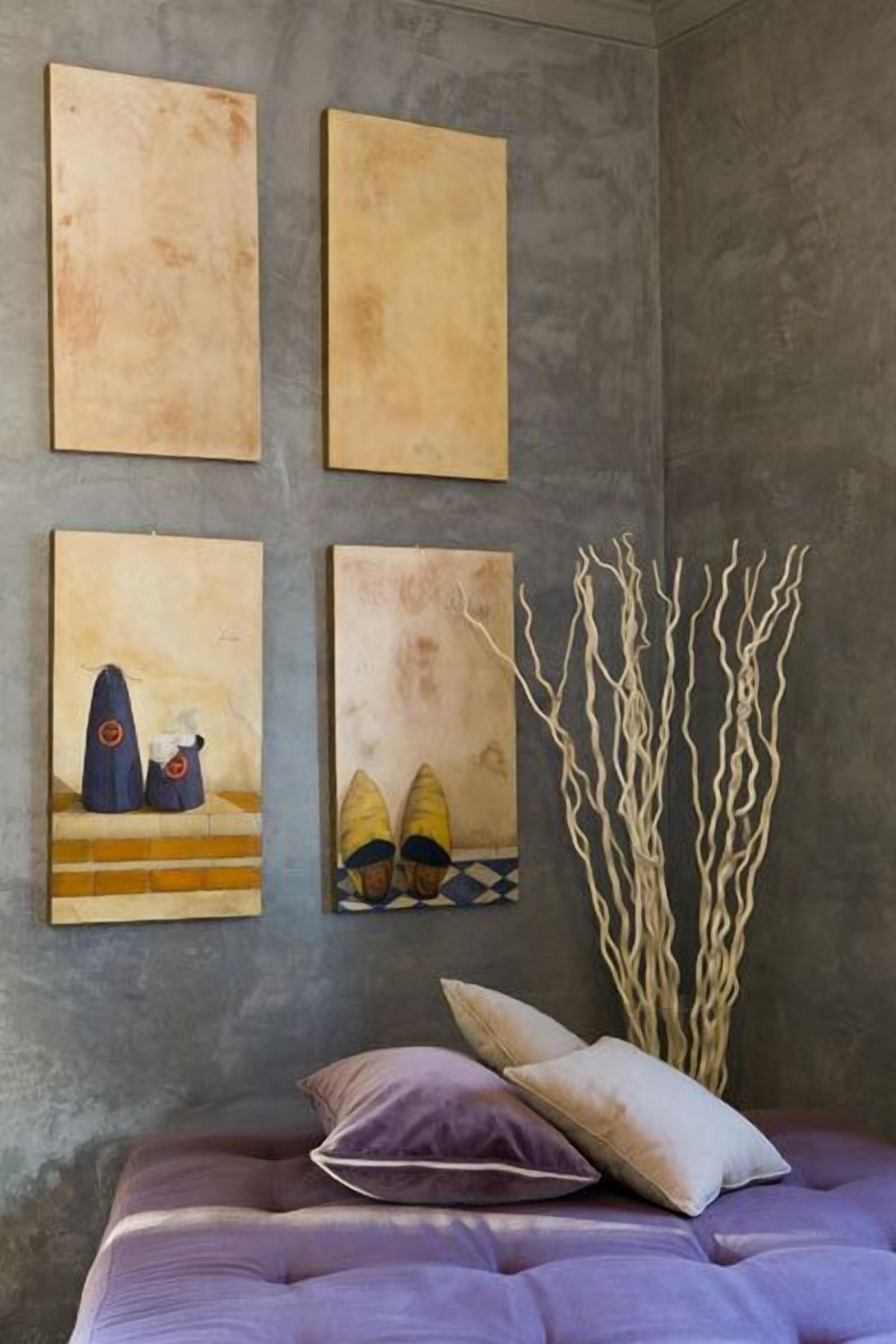 Une chambre à coucher avec un lit, des oreillers et quatre tableaux accrochés au mur.