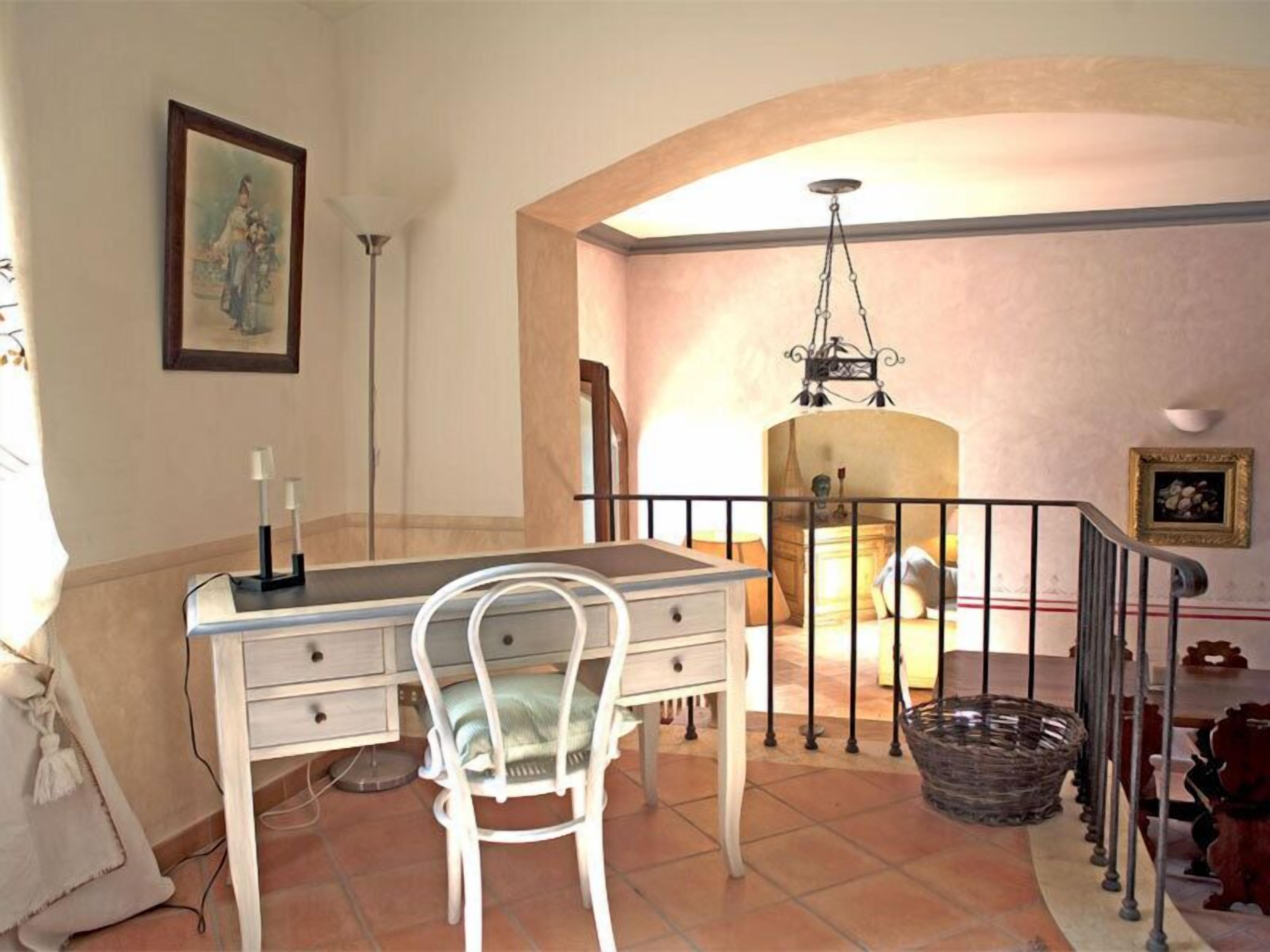 A dining area with a table and chairs, a chandelier, and a staircase.