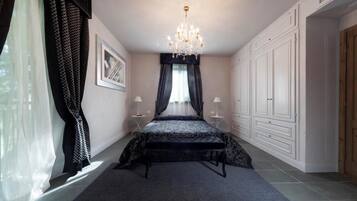 Een slaapkamer met een bed, een kroonluchter, een kledingkast en een raam met gordijnen.