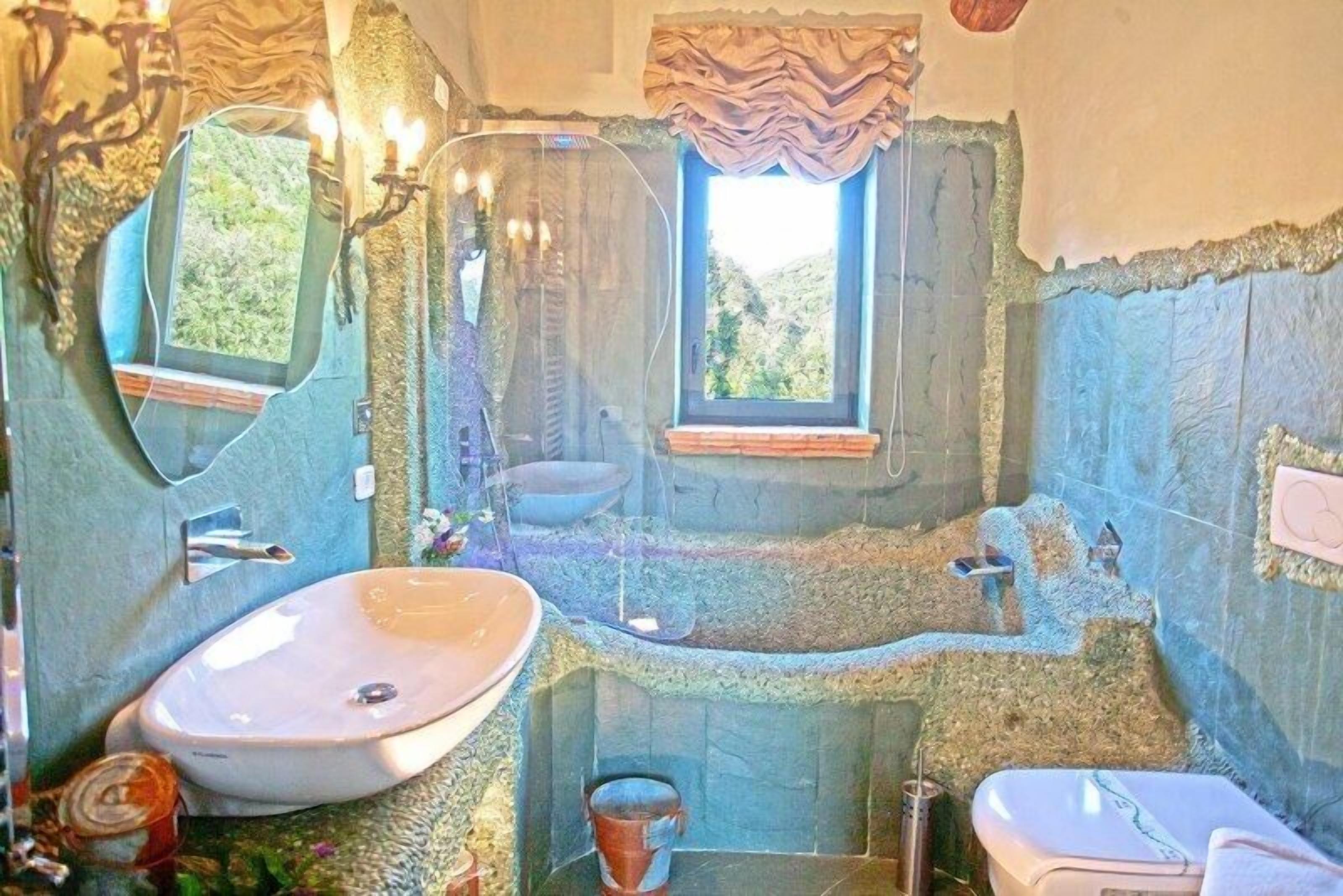 A bathroom with a stone sink, a bathtub, and a toilet.
