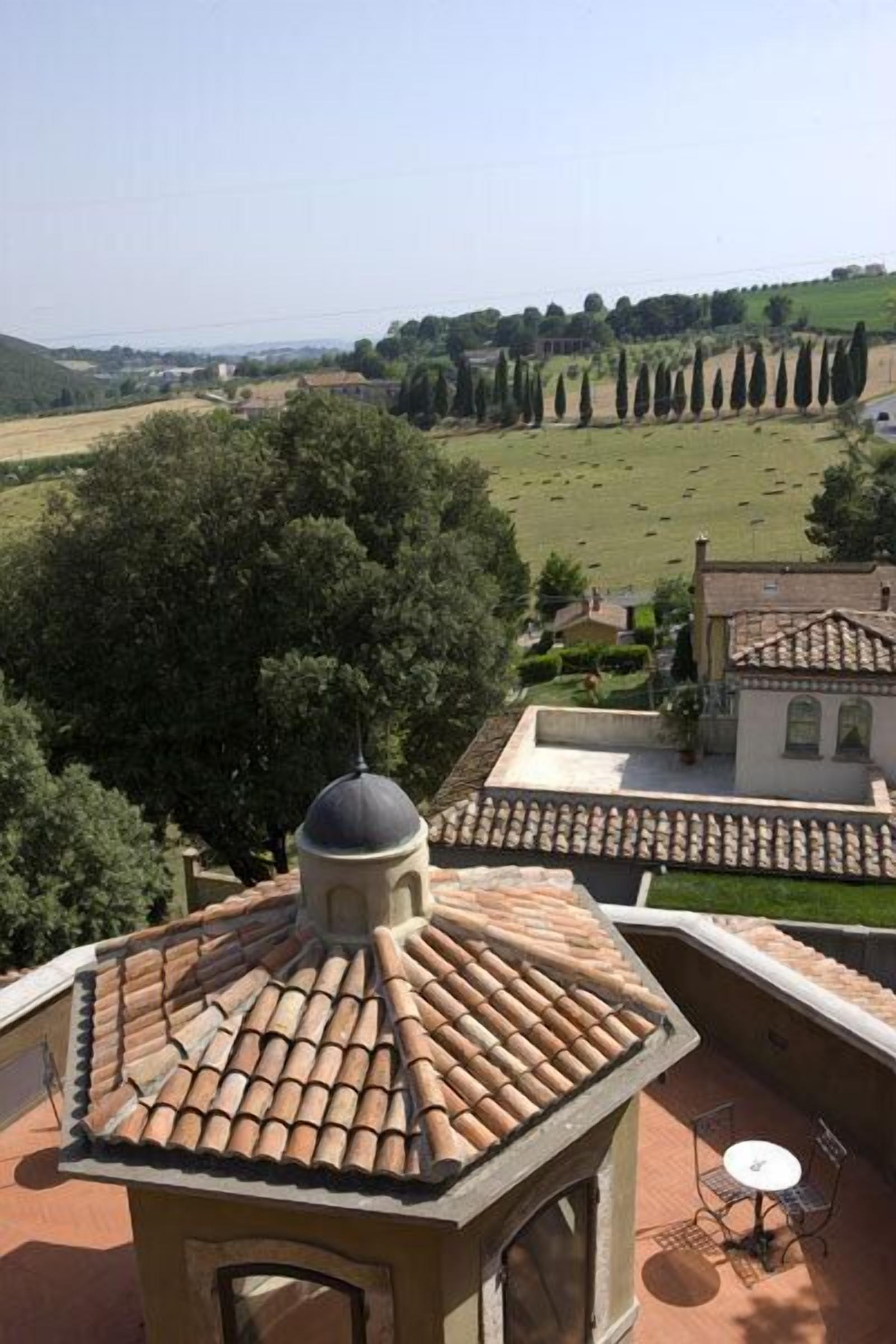 Una terraza en la azotea con tejas de terracota, una pequeña estructura en forma de cúpula y una mesa con sillas.