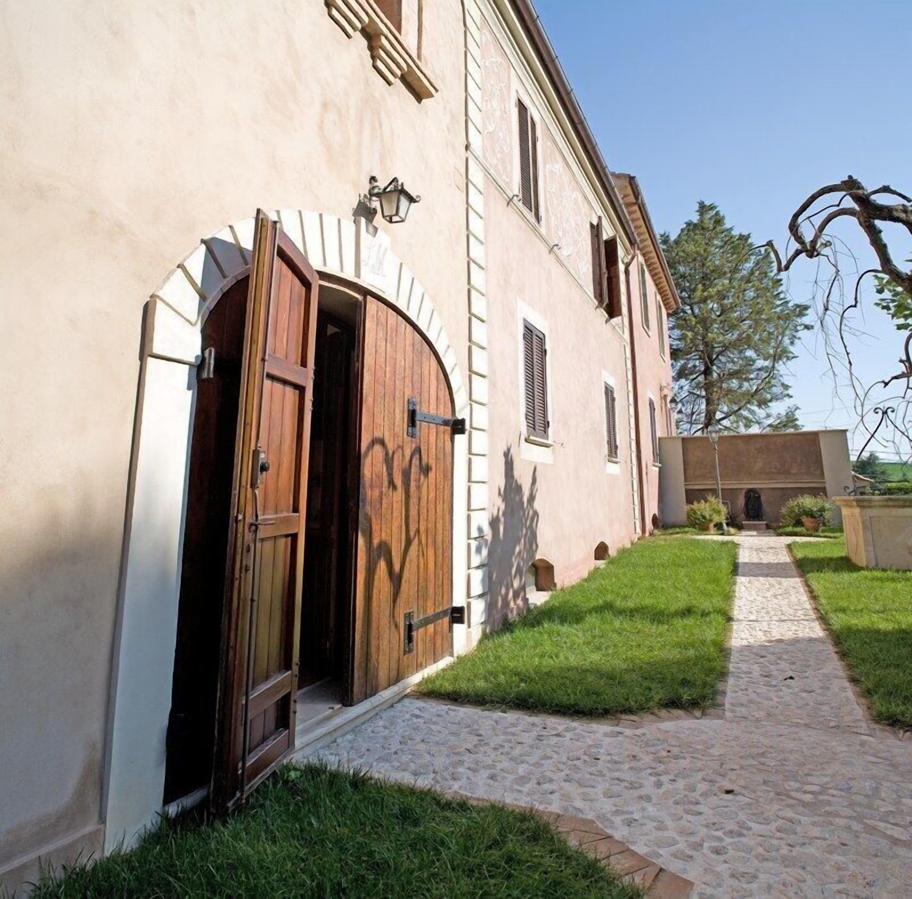 Un edificio con una puerta de madera grande, un camino de piedra y una zona con césped.