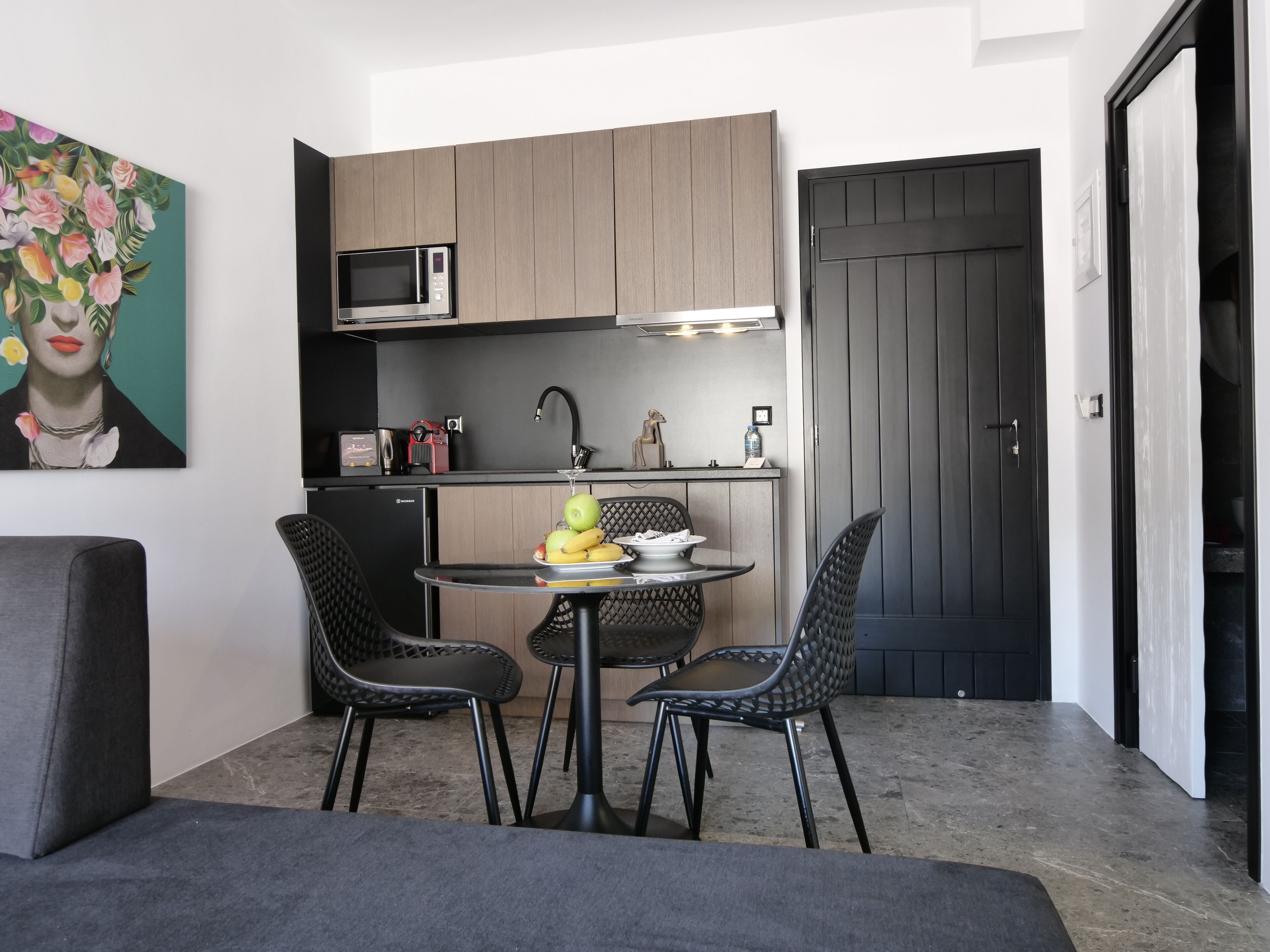 A compact kitchen with a microwave, sink, and a small dining area with chairs and a table.