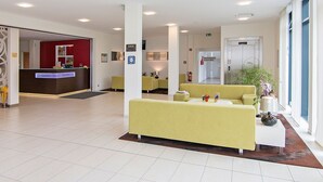 A hotel lobby with a reception desk, seating area, and a fire exit. - Qualitel Hotel Hilpoltstein (Hilpoltstein)