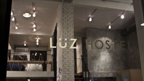 A modern interior with exposed brick walls, a staircase, and hanging pendant lights. - Luz Hostel (Bangkok)