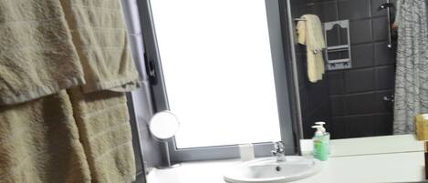 Un baño con lavadora, lavamanos, espejo e inodoro.