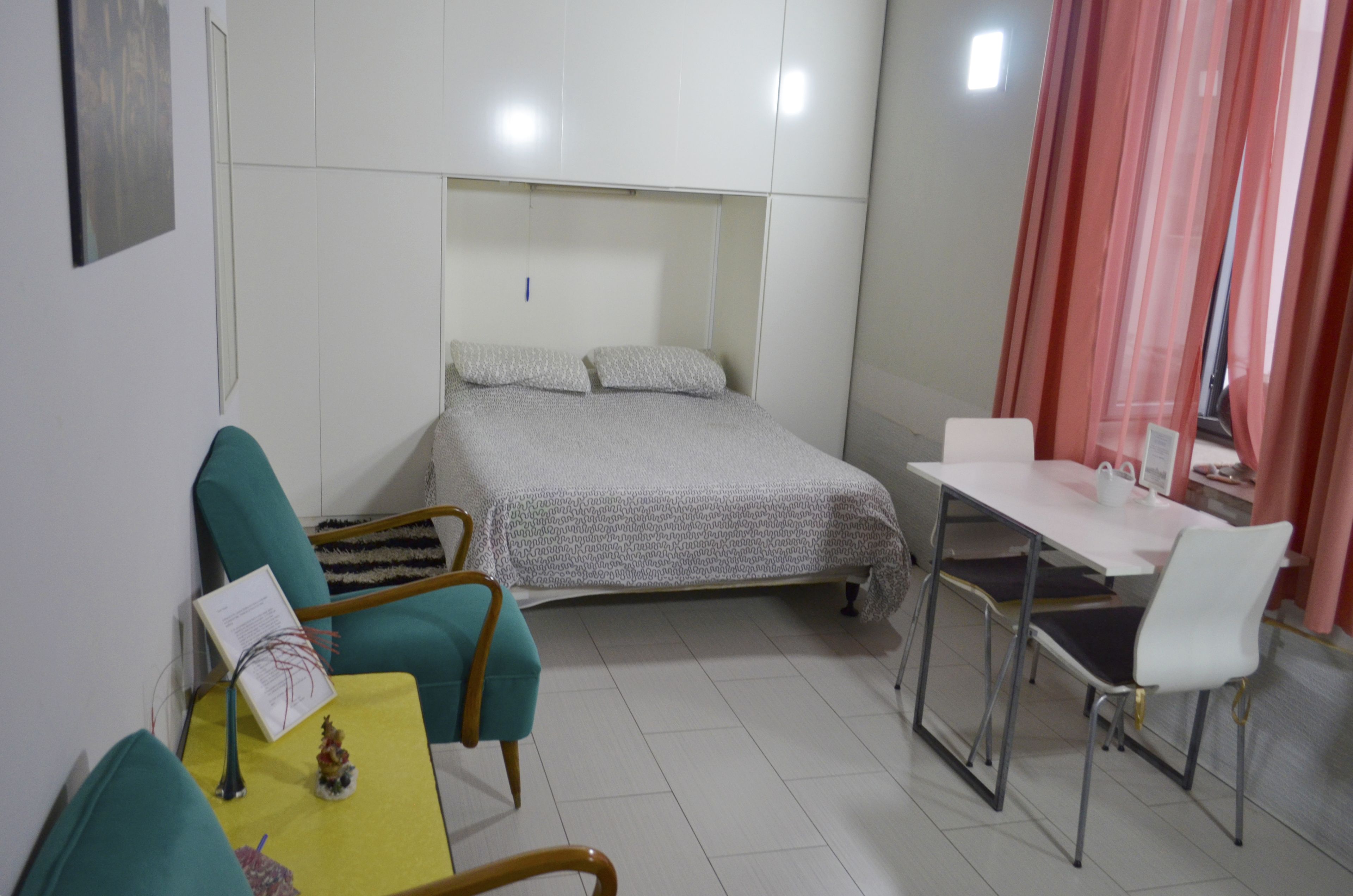 A small, clean room with a bed, a desk, and a chair.