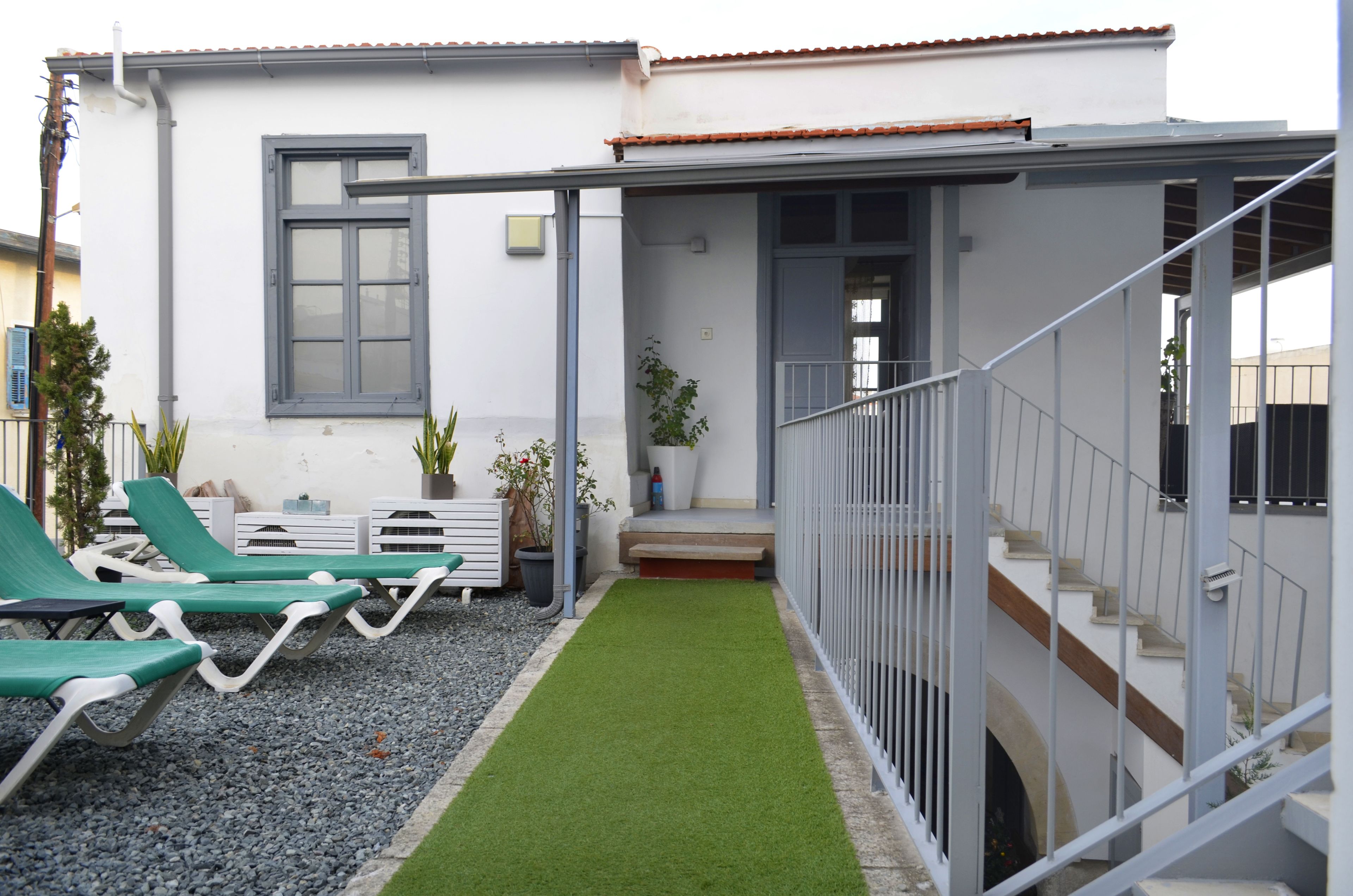 Ein kleines Haus mit überdachter Veranda, einer Treppe und einem kleinen Rasen mit künstlichem Grün.