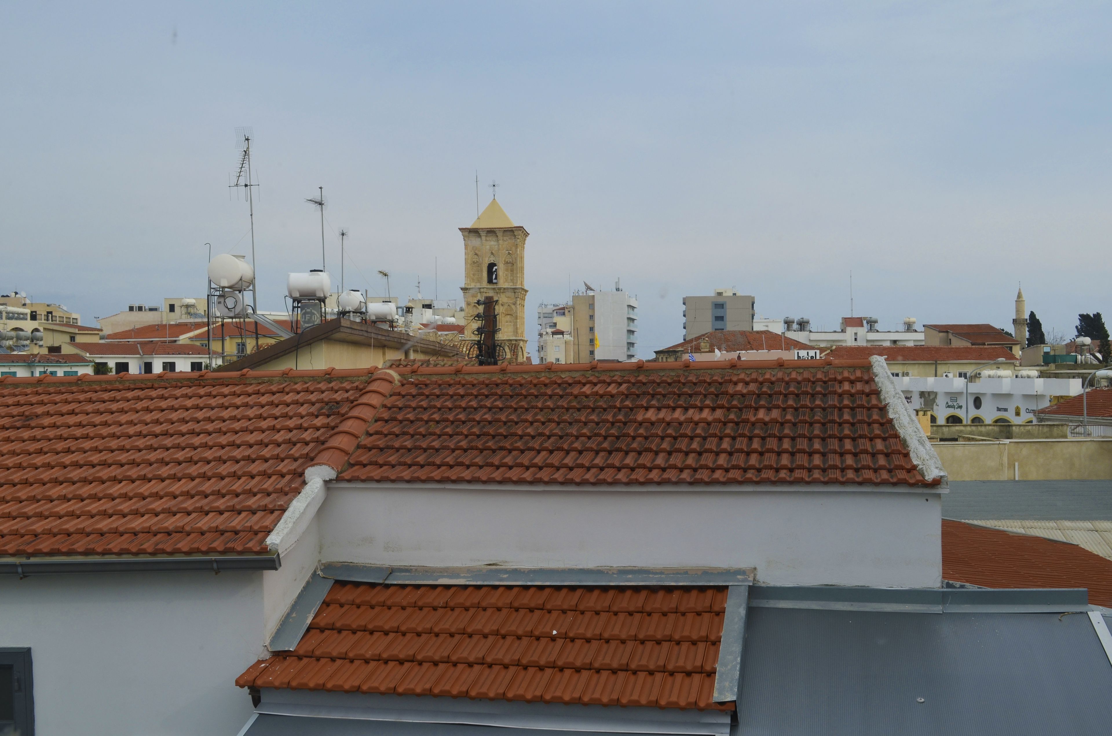 Un paisaje urbano con una torre destacada y varios edificios con techos de tejas rojas.