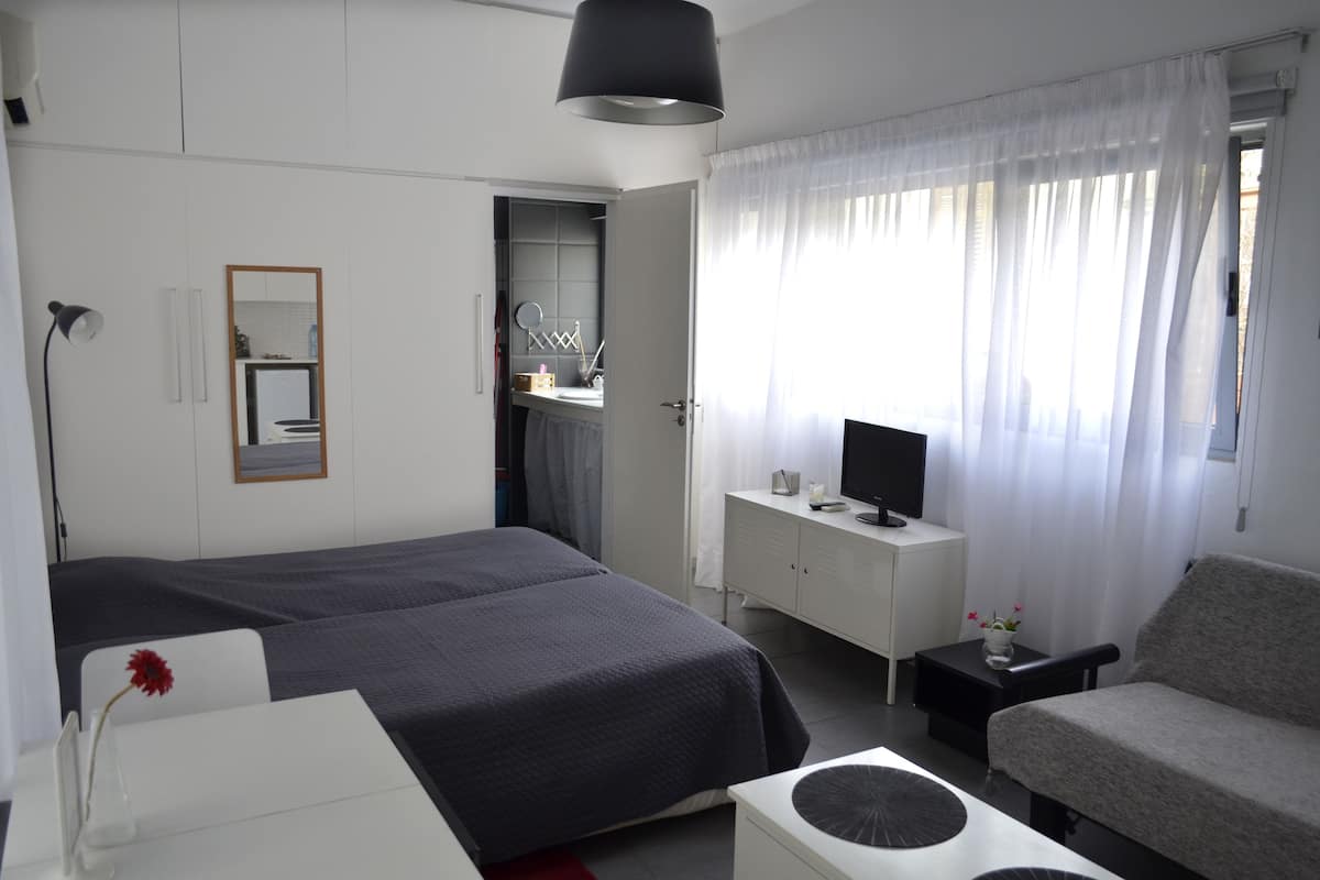 Una habitación de hotel con cama, escritorio, silla, televisor y armario.