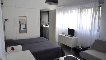 Una habitación de hotel con cama, escritorio, silla, televisor y armario.