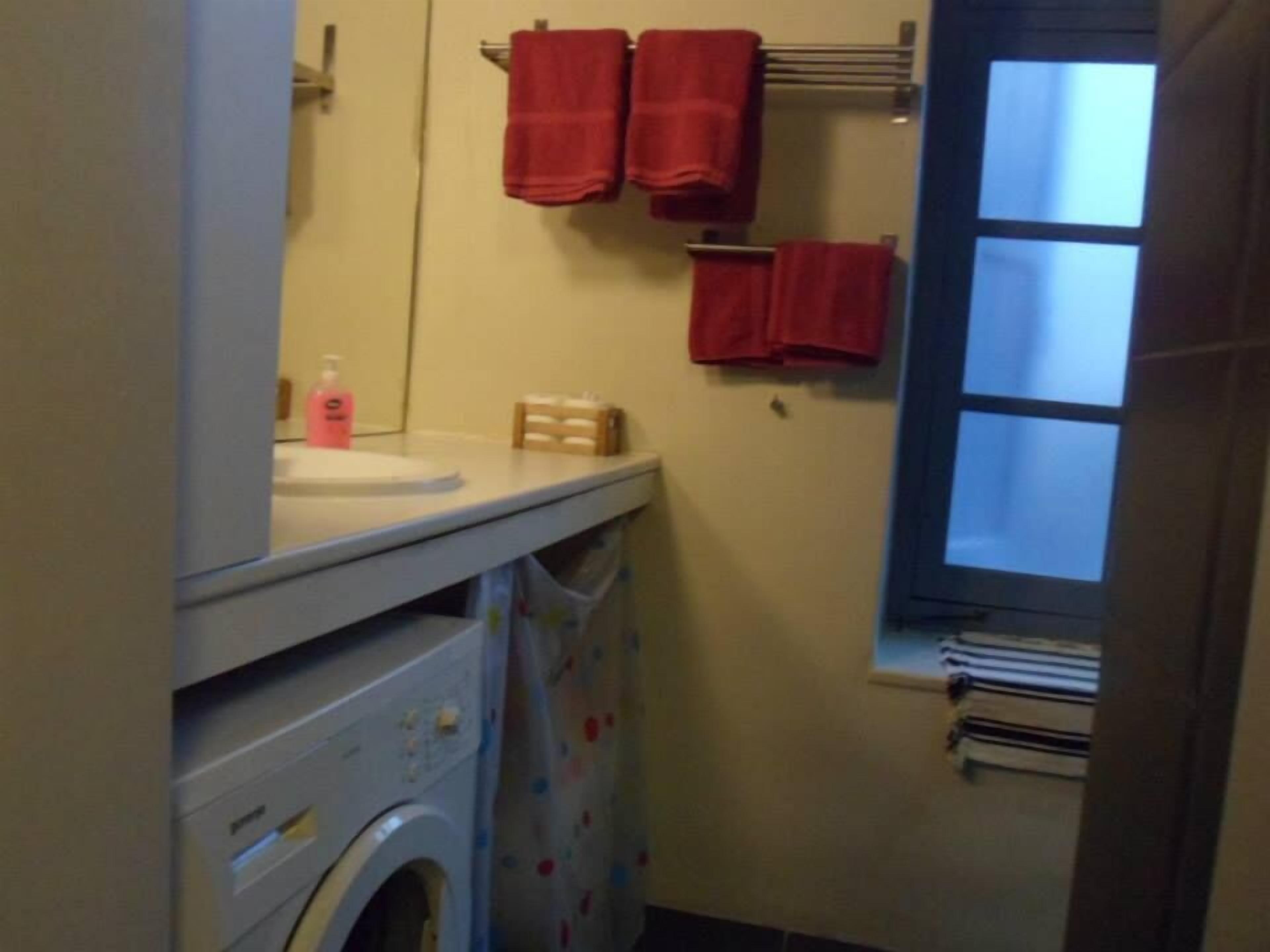 A compact bathroom with a washing machine, a sink, and a window.