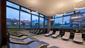 Un área de spa moderna con ventanas amplias, sillones reclinables y vistas a montañas.