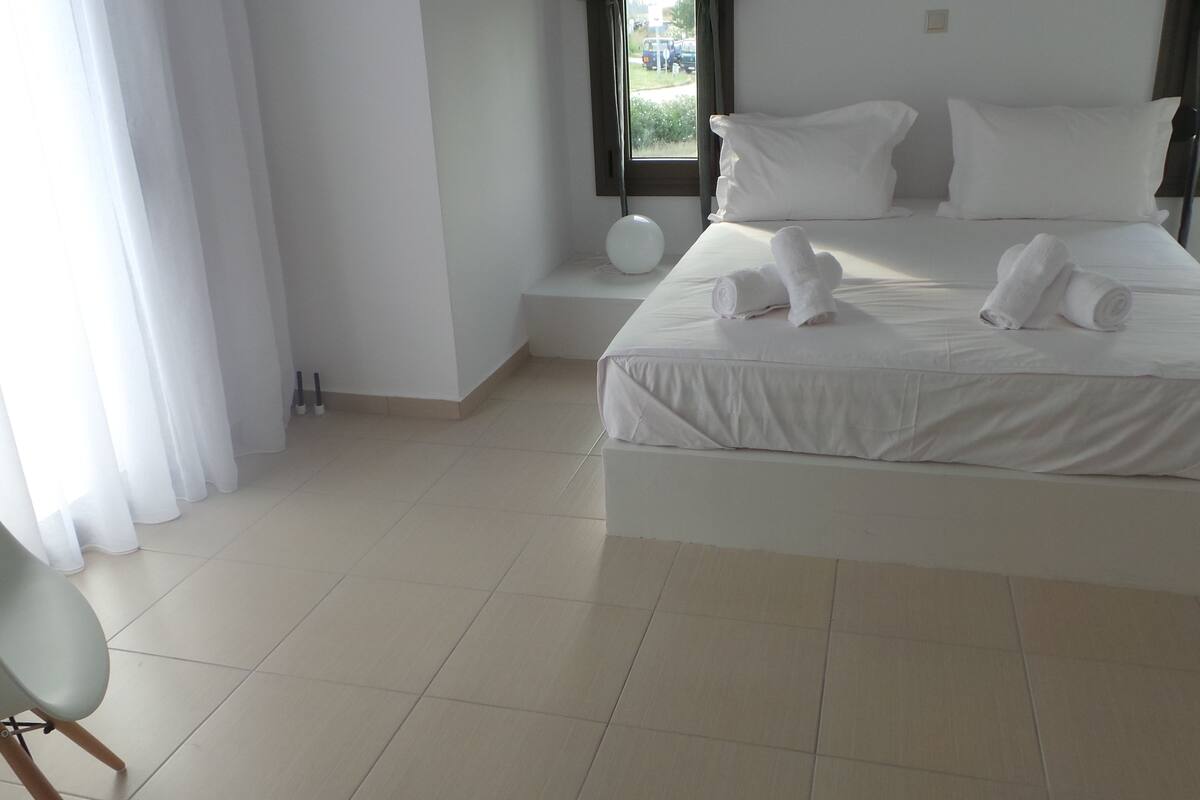 Ein modernes Hotelzimmer mit einem großen Bett, zwei Nachttischen und einem Sessel.