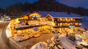 A large, well-lit hotel with multiple guest rooms, a restaurant, and a ski lift in the background. - Romantic & Family Hotel Gardenia (Selva di Val Gardena)