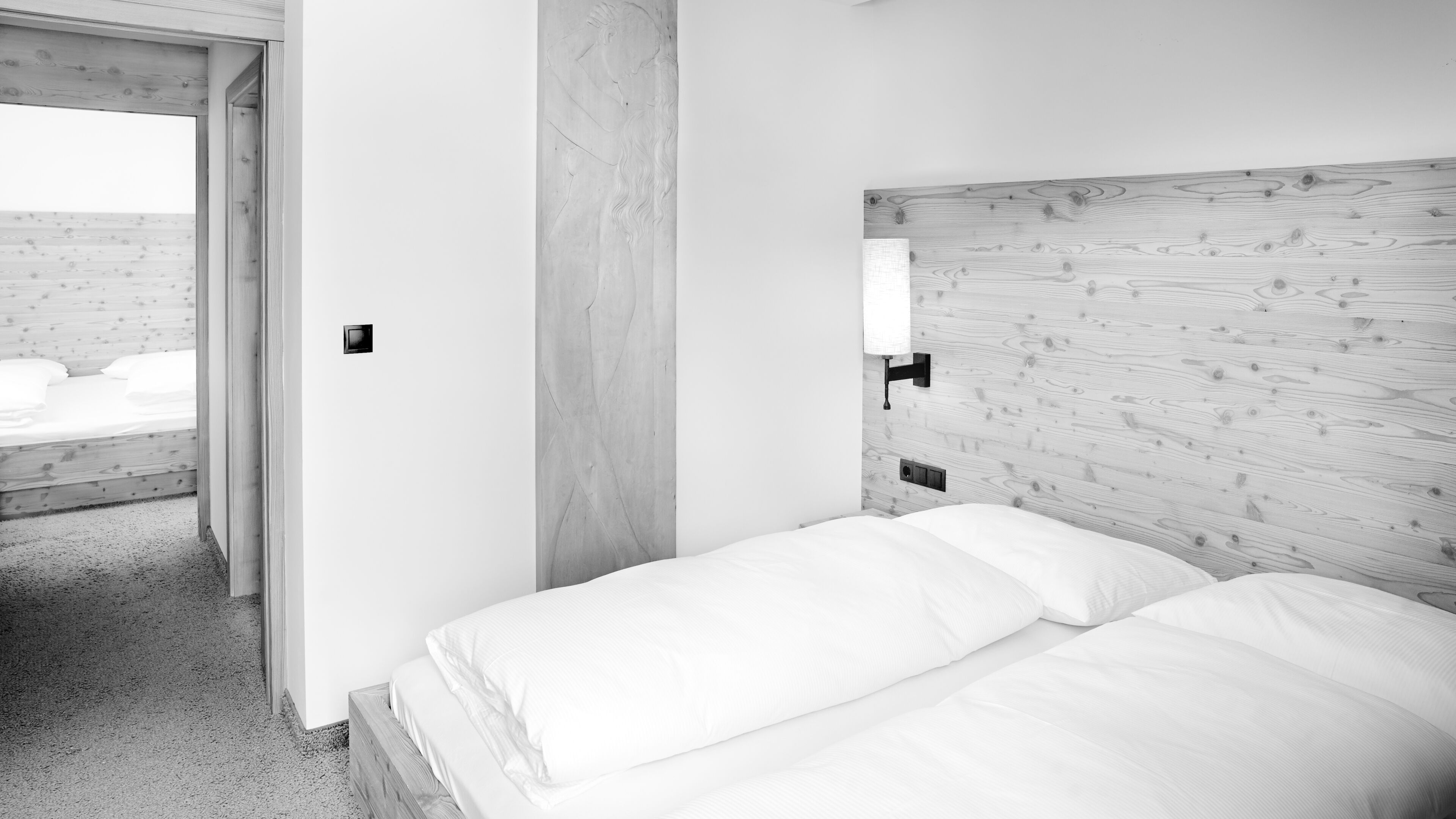 A minimalist bedroom with a wooden headboard, a single bed, and a small bedside table.