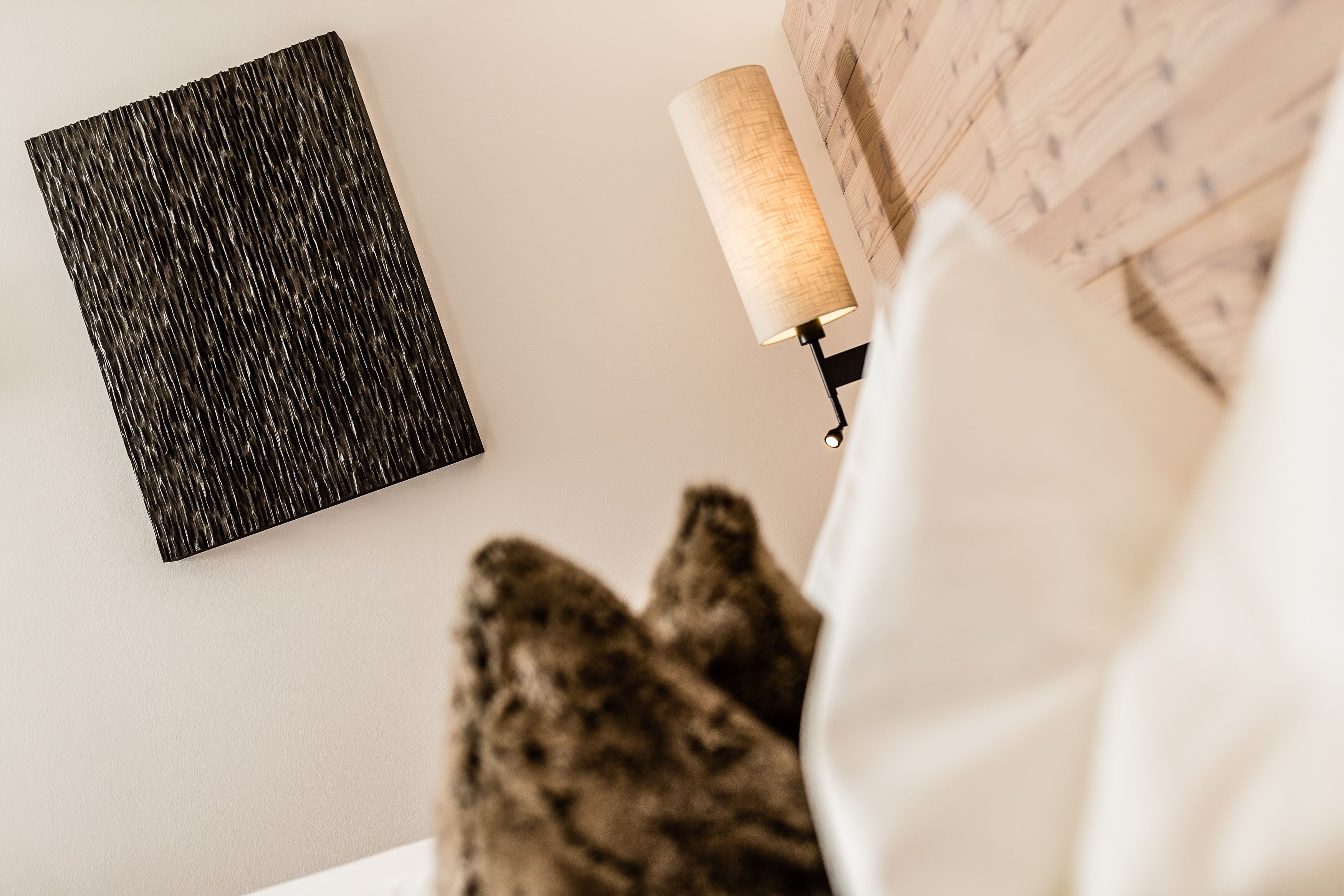 Een kamer met een wandkunstwerk met textuur, een lamp en een kamerbreed tapijt met patroon.