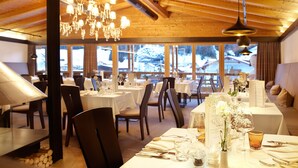 Un restaurant avec des plafonds en bois, des lustres et des tables dressées pour le dîner.