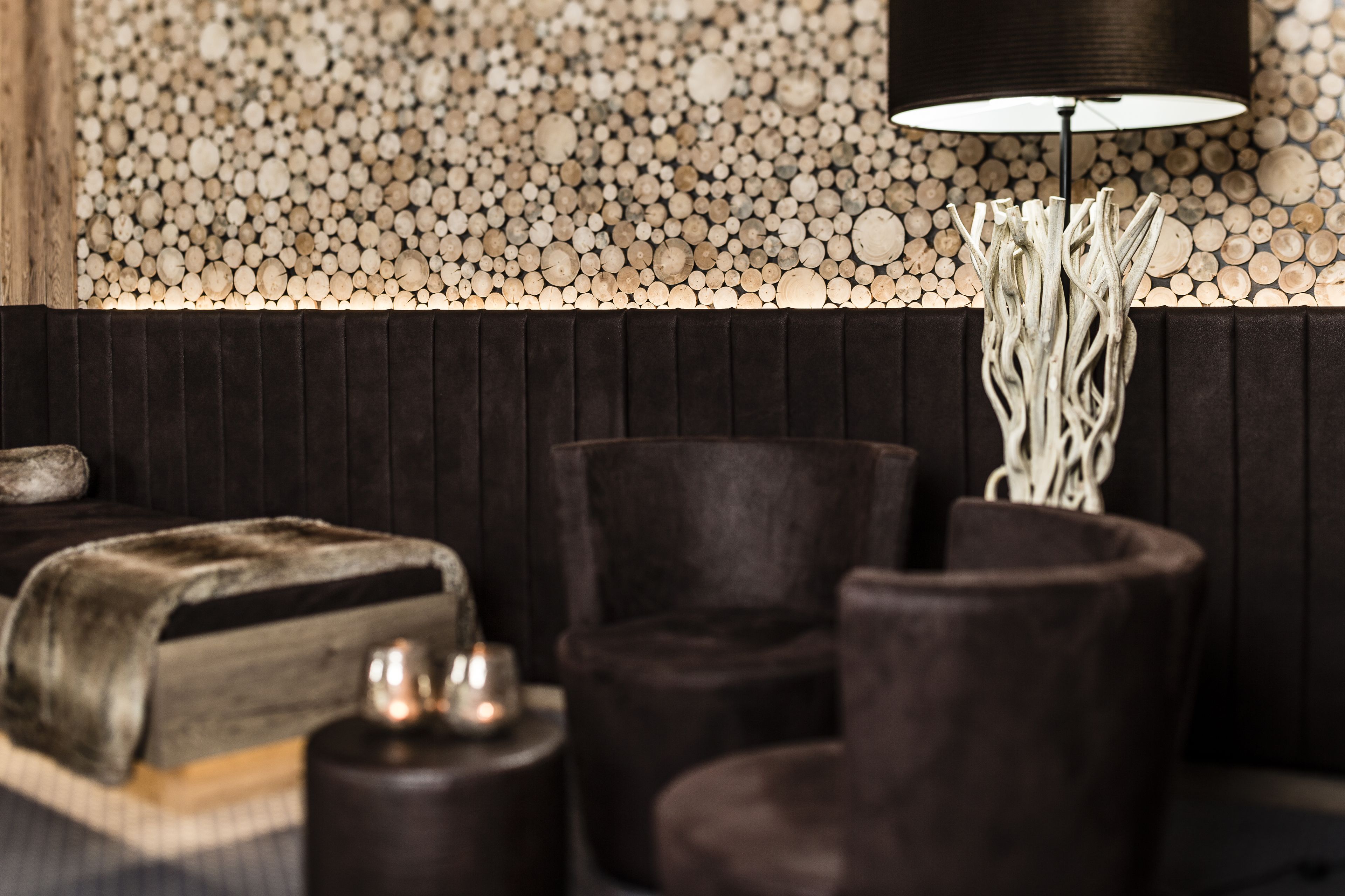 Una sala de estar moderna con un panel de madera oscura, una mesa redonda con velas y una lámpara de pie.