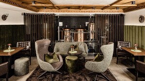 A modern living room with a fireplace, leather chairs, a round coffee table, and a dining area with a wooden table and chairs. - Boutique & Fashion Hotel Maciaconi (Selva di Val Gardena)