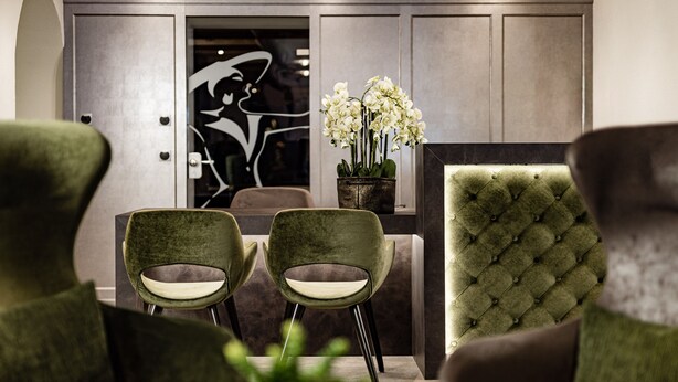 Un interior moderno con sillas tapizadas en verde, un sillón capitoné y una mesa de comedor.