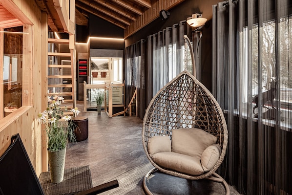 A modern interior with a hanging chair, wooden shelves, and a view of the outdoors.
