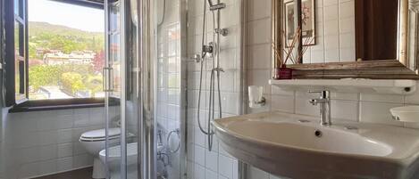 A bathroom with a glass-enclosed shower, a sink, and a large mirror.