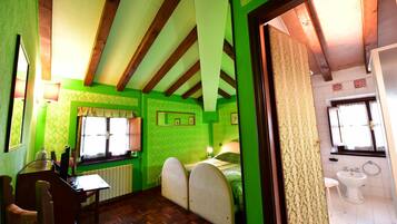 Quarto com teto de madeira, paredes verdes, cama com cabeceira, escrivaninha com cadeira, radiador e janela.