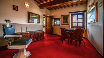 Una habitación con alfombra roja, una silla azul, un armario de madera y una mesa de comedor con sillas.