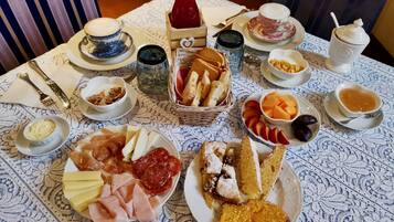 Una mesa de desayuno con diferentes alimentos y bebidas, como pasteles, queso y una botella de jugo.