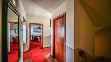 A hallway with a red carpet leading to a dining area with chairs and a table.