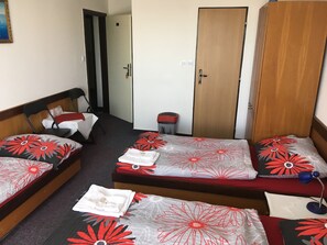 A hotel room with two single beds, a wooden wardrobe, a small trash bin, and a table with a red tablecloth. - ABC Hotel (Nitra)