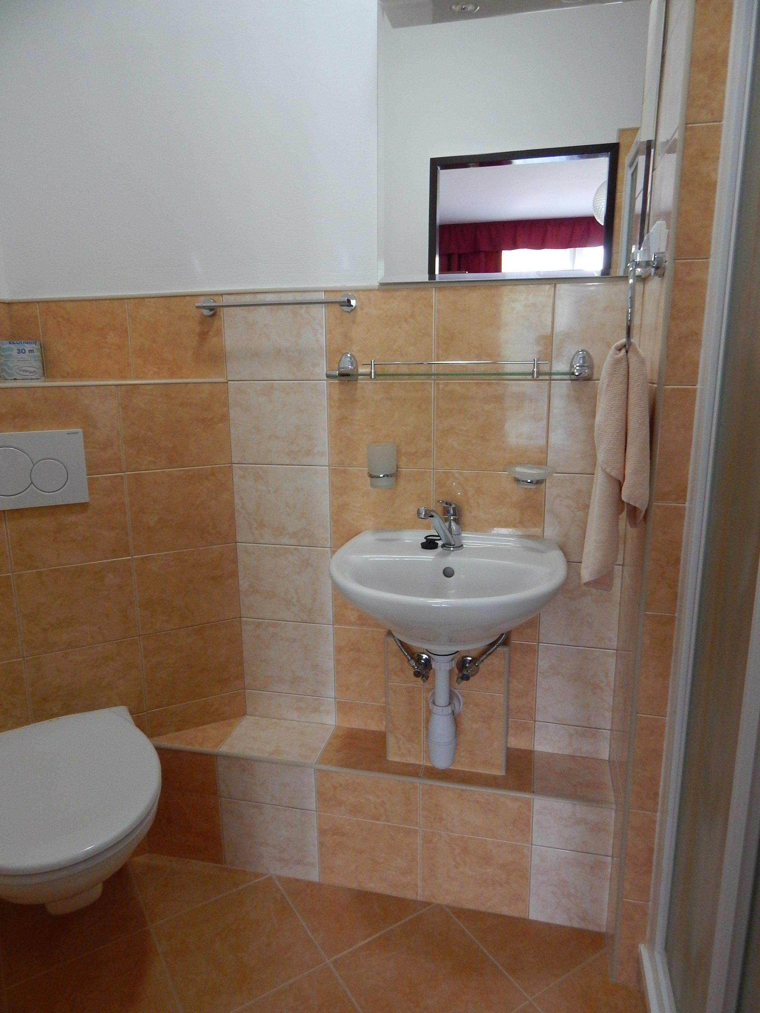 A bathroom with a white sink, a mirror, and a towel hanging on the wall.