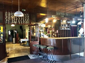 A bar area with a reception desk, stools, hanging lights, and a wooden ceiling. - ABC Hotel (Nitra)