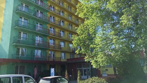 Een meerhoog hotel met balkons, een parkeersbord en een restaurant genaamd 'ABC Hotel'.