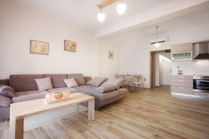 A modern living room with a sofa, a wooden coffee table, and a dining area with chairs and a table. - Petra Thea (Kalamata)