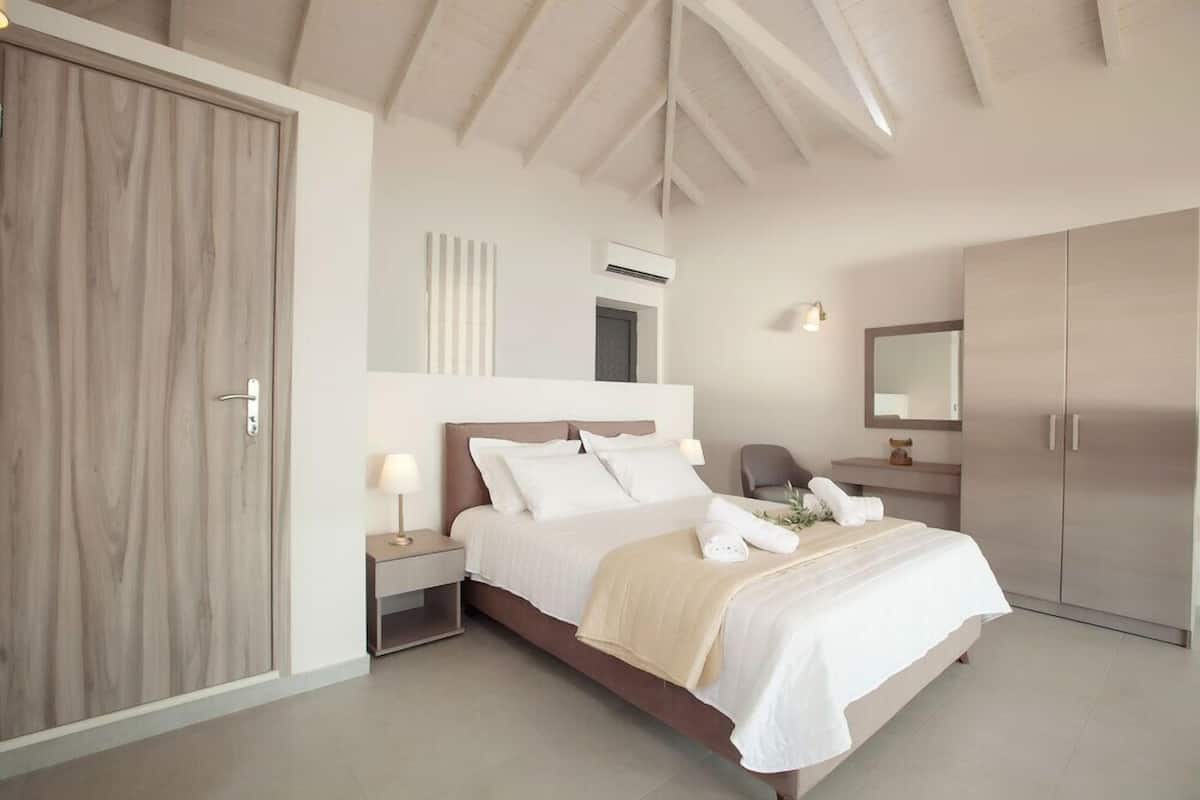 A modern bedroom with a large bed, bedside tables, a wardrobe, and a mirror.