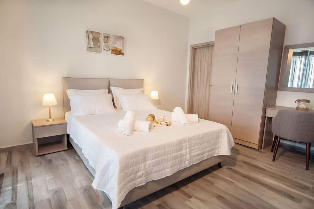 A neatly arranged bedroom with a bed, bedside tables, a wardrobe, and a desk with a chair.