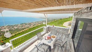 A balcony with a table set for dining, overlooking a coastal landscape. - Petra Thea (Kalamata)